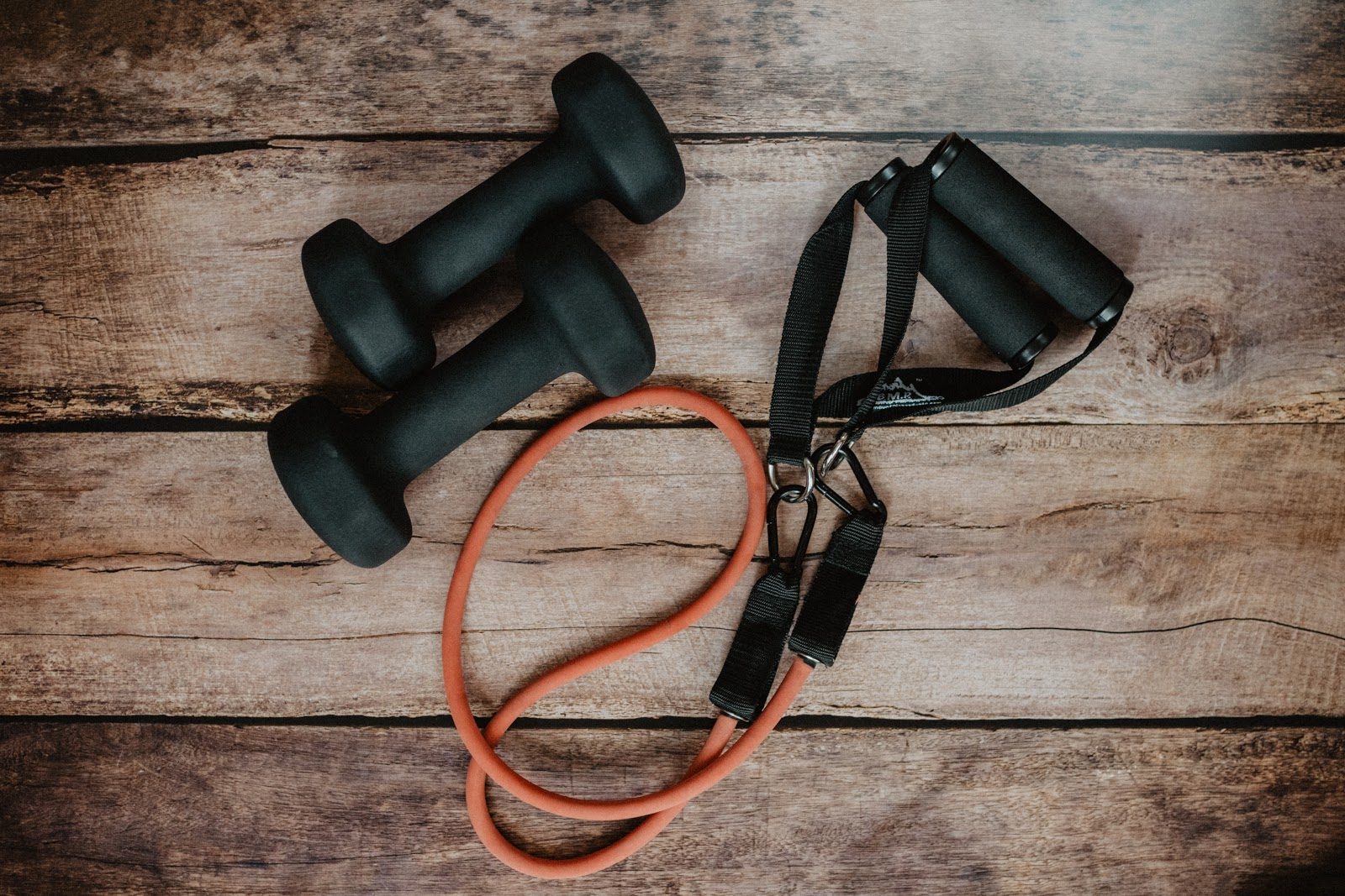 Workout weights and resistance bands on wooden surface
